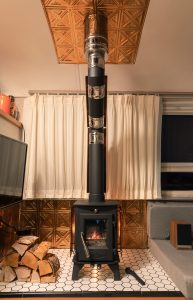 A tiny wood stove looks elegant with a copper roof and copper fire wall behind the stove.